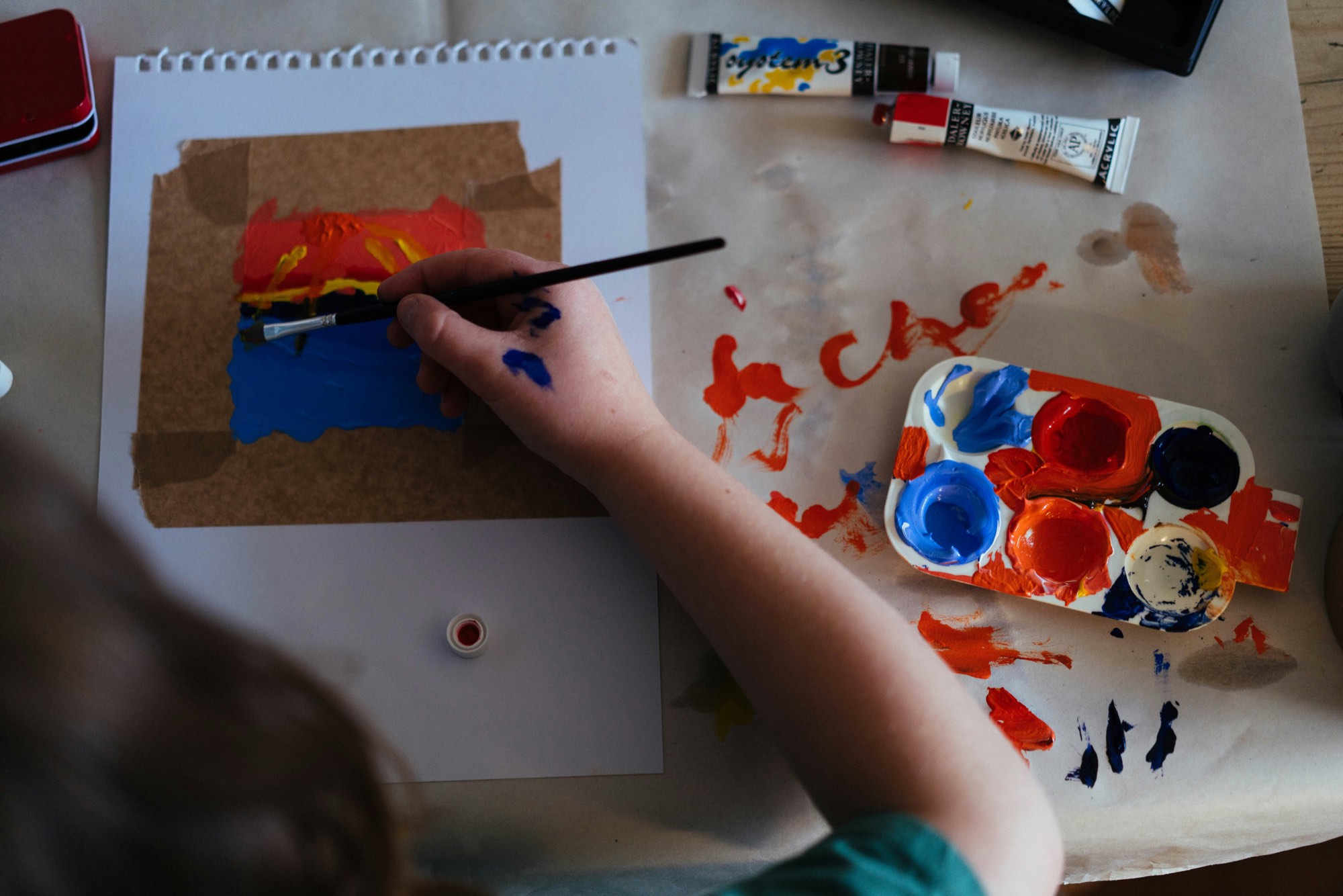Vu de dessus, un enfant peint en rouge et en bleu, de la peinture plein la main